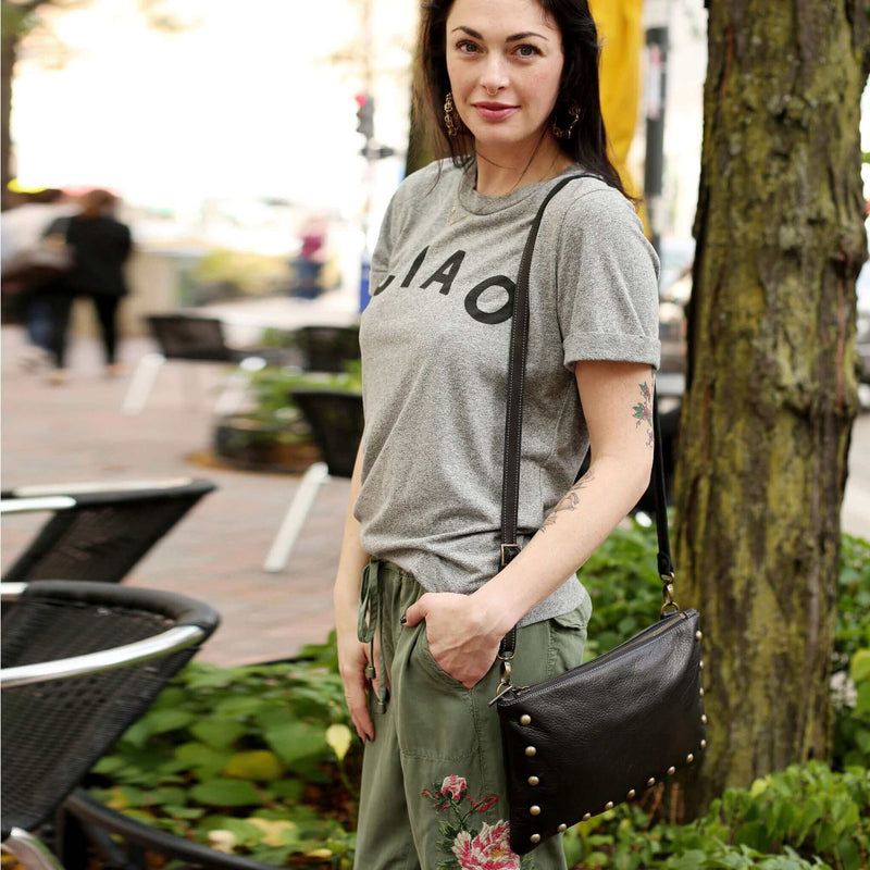 Woman wearing black studded bag in full-grain leather as a small crossbody bag in city street