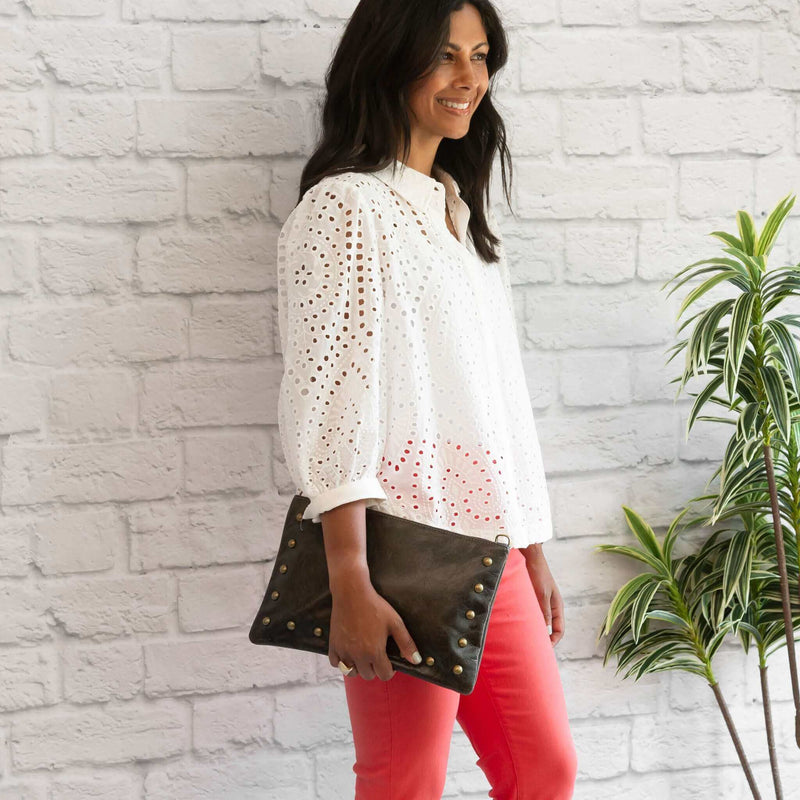 Woman wearing dark charcoal studded bag in full-grain leather as a clutch