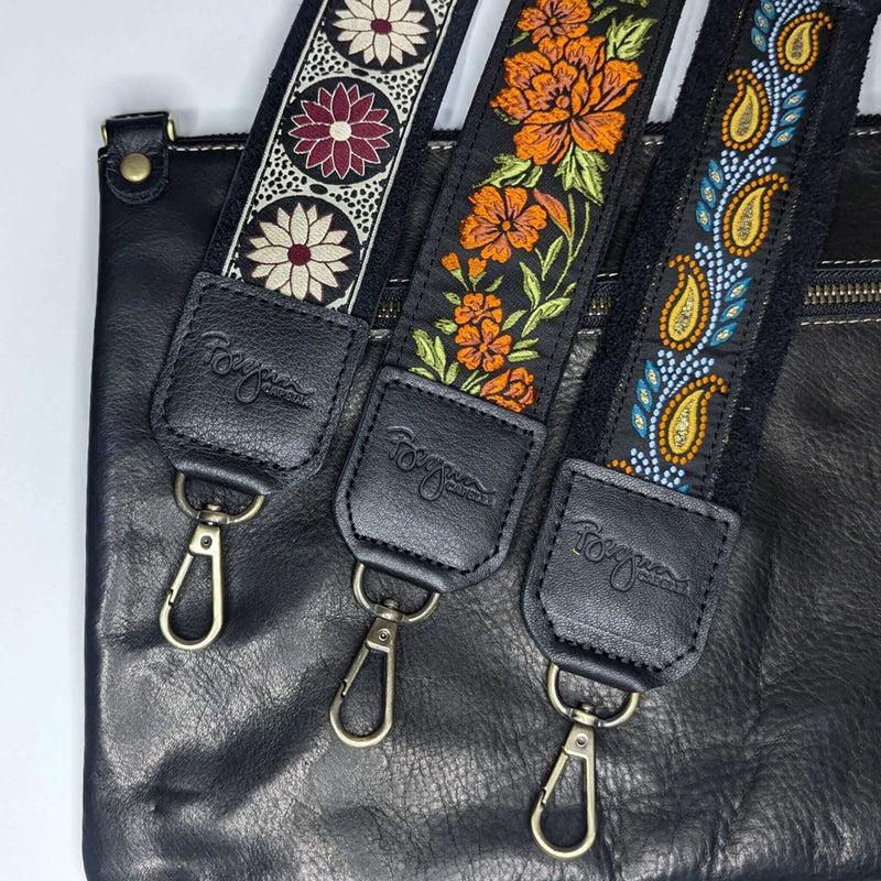 Back view of black full-grain leather bag paired with three matching guitar purse straps in woven jacquard prints