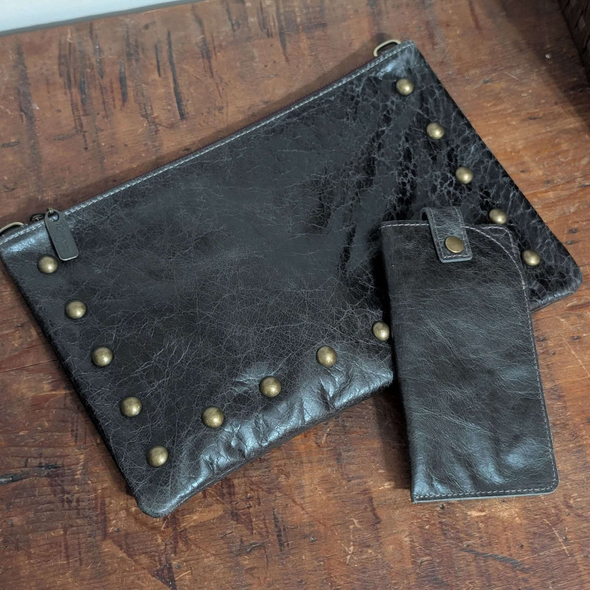 Nikki Studded Crossbody Bag in black leather with studded design and matching wallet on wooden background.