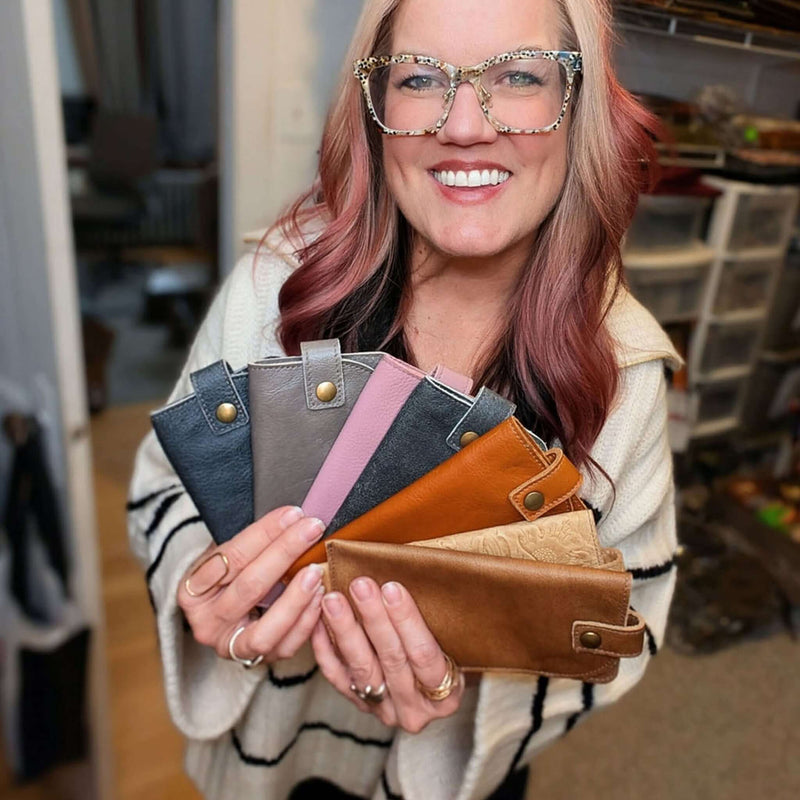 Woman holding multiple Leather Eyeglass Cases in various colors, showcasing the stylish design and functionality.