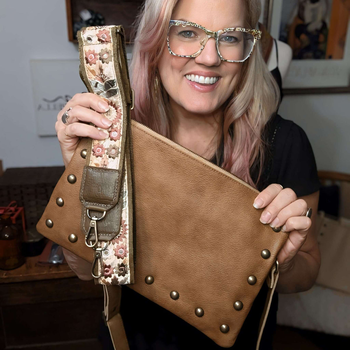 Designer Brynn Capella holding a golden brown studded leather crossbody clutch with our Chocolate Sunflower Lizzy bag strap