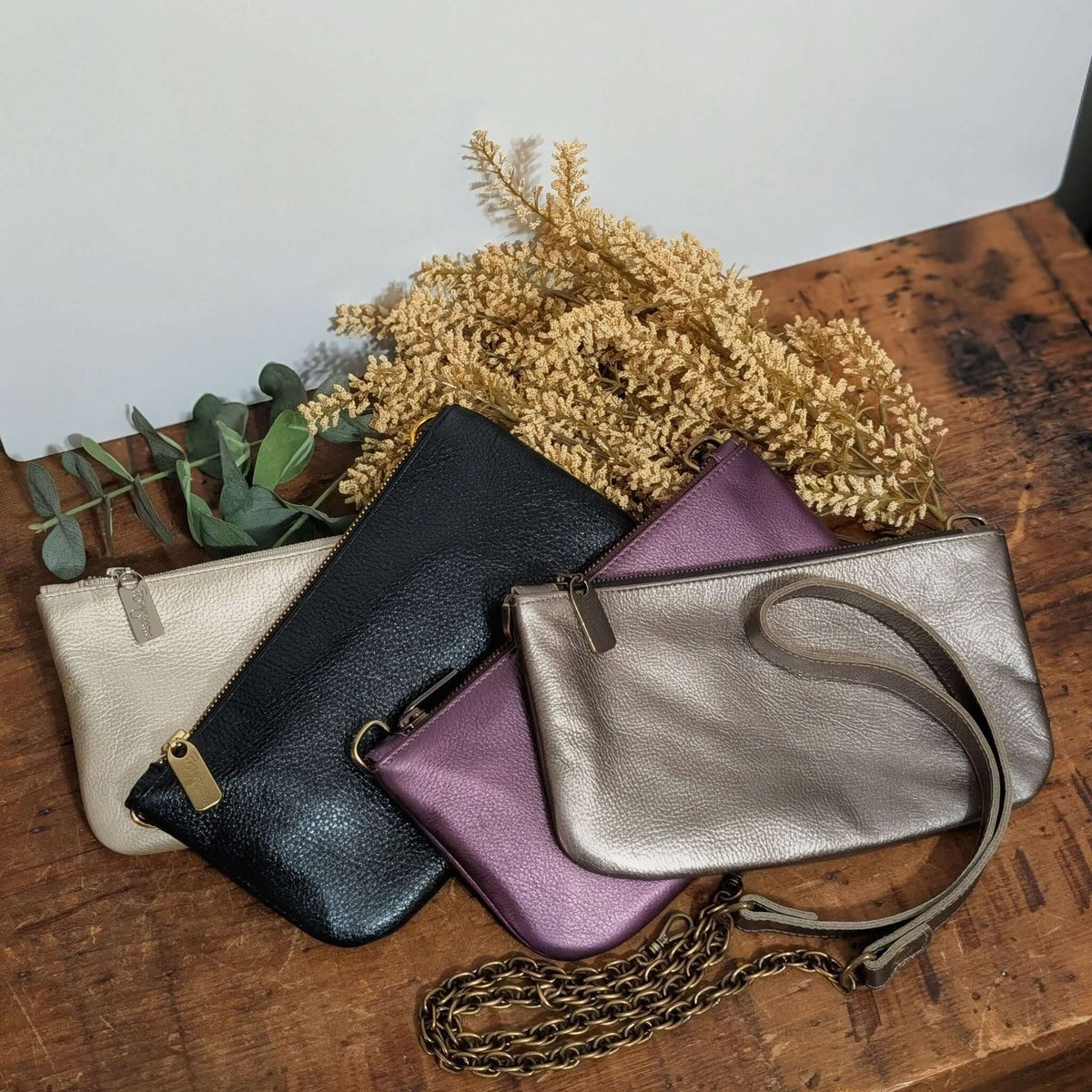 Metallic Leather Bag collection featuring antique pewter and other colors with a stylish design on a wooden surface.