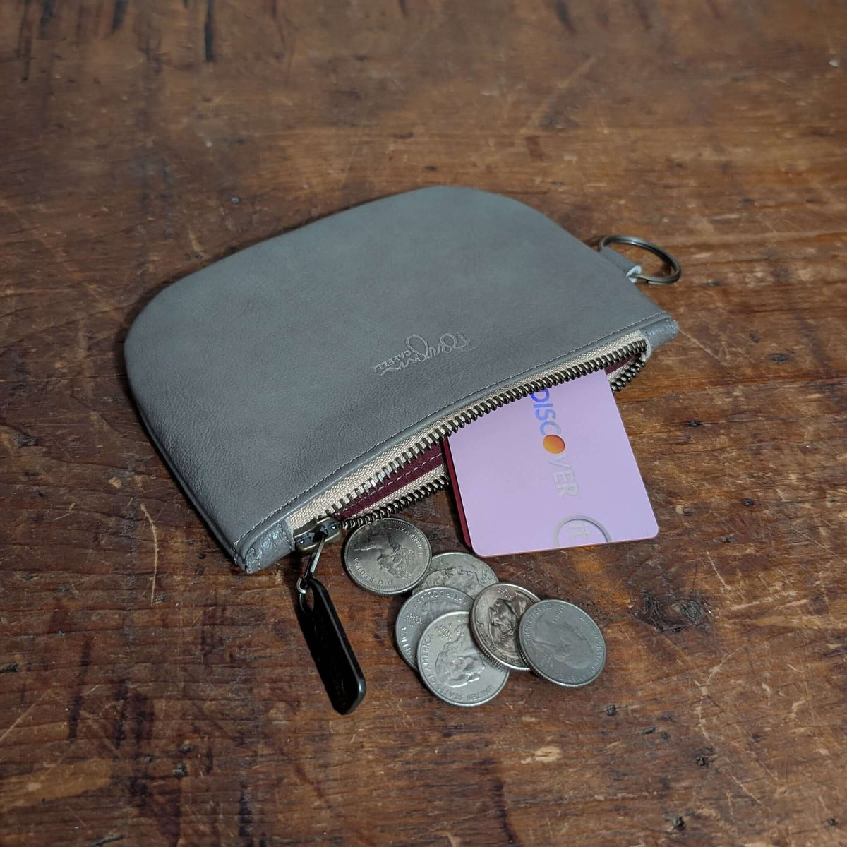Dylan leather coin purse in gray with coins and a card on a wooden surface - leather coin purse.