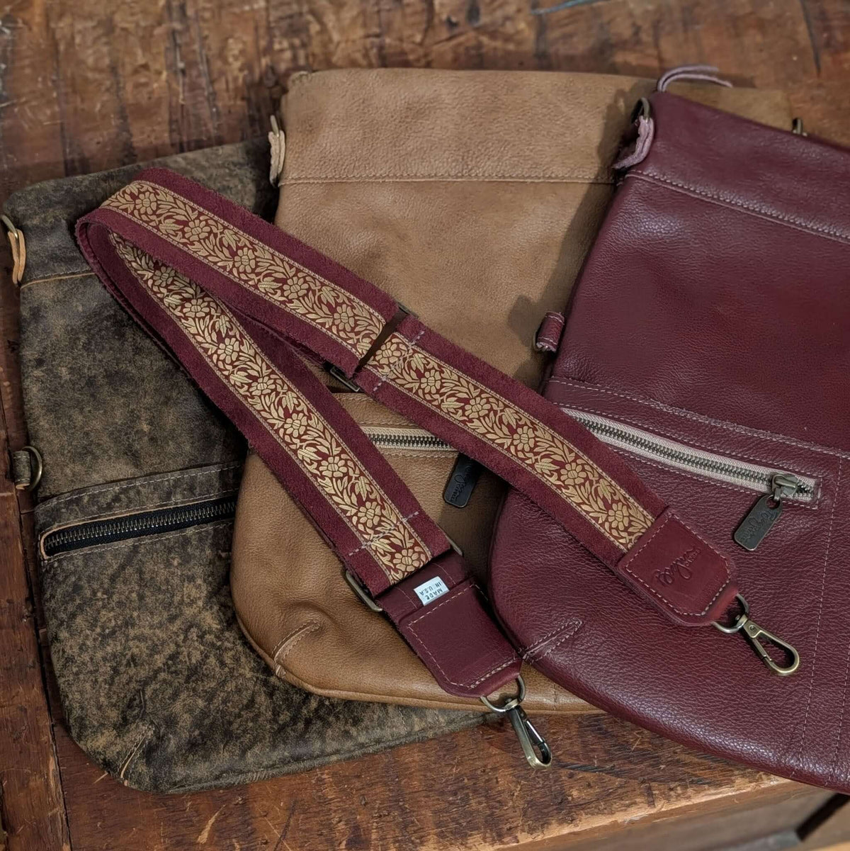 Lizzy Guitar Bag Strap in maroon with gold floral design on three different leather bags that pair well with it.